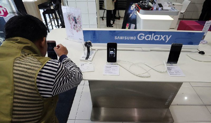 A visitor tries the Samsung Electronics' S7 edge smartphone at a shop of South Korean mobile carrier in Seoul, South Korea, Thursday, Oct. 13, 2016. Samsung Electronics says it has expanded its recall of Galaxy Note 7 smartphones in the U.S. to include all replacement devices the company offered as a presumed safe alternative after the original Note 7s were found prone to catch fire. (AP Photo/Lee Jin-man)