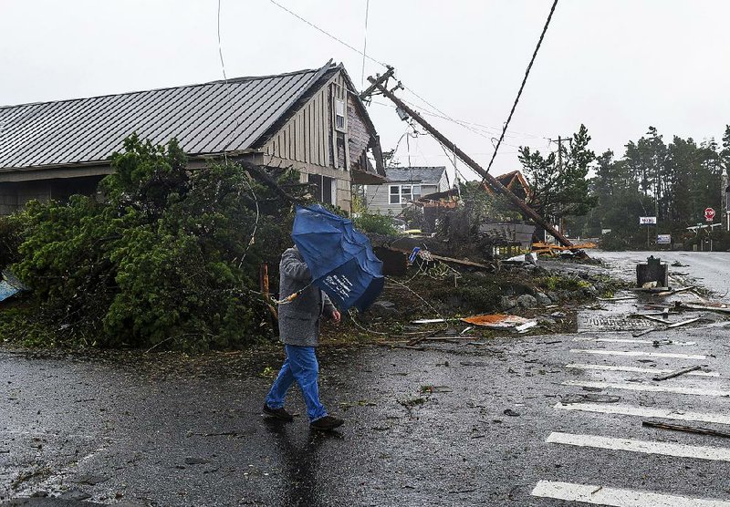 A man battles the wind as he walks past debris after a tornado touched down Friday in Manzanita, Ore. 