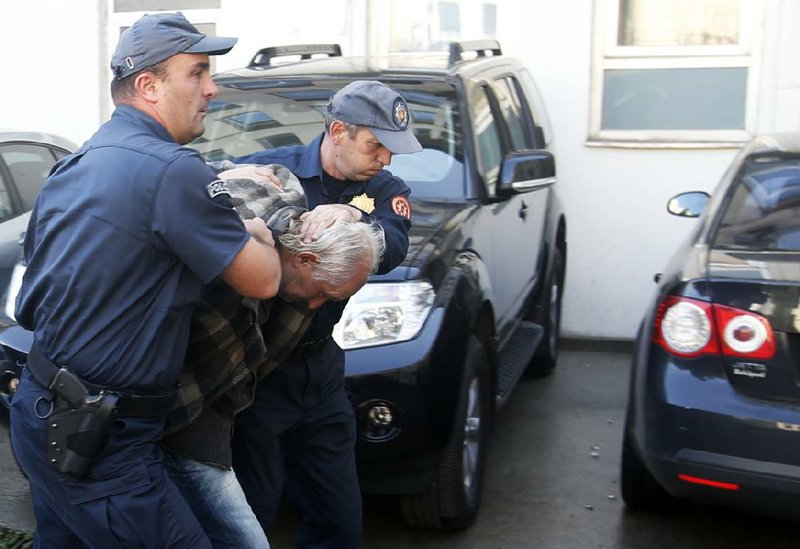 Police in Podgorica, Montenegro, escort a man arrested in a suspected Serbian plot to attack Sunday’s parliamentary election and seize the country’s prime minister.