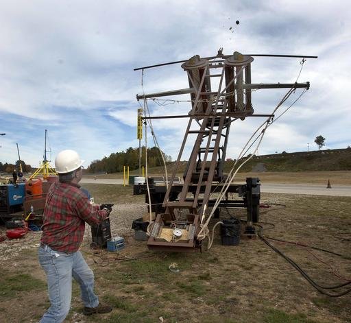 In this Saturday, Oct. 15, 2016 photo, Eric Ludlam, from Framingham, Mass. pulls the trigger on his pumpkin thrower "Mista Ballista" in Loudon, N.H. A design from a 400 BC rock thrower tosses a pumpkin more than 1,000 feet. Sixteen teams competed over the weekend at New Hampshire Motor Speedway for the longest pumpkin toss.