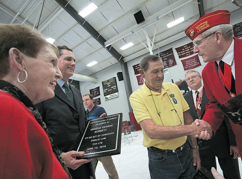 Marine veteran John Smallwood (right) of Jacksonville congratulates Dick Bennett, Harold Bennett’s brother, at Monday’s dedication ceremony at Perryville High School for the Harold George Bennett Post Office. Laura Vaught, Bennett’s sister, stands next to U.S. Rep. French Hill.