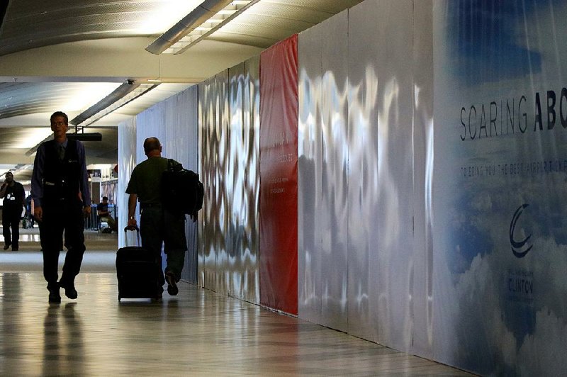 Passengers walk down the concourse Tuesday past a wall built in front of a gate area that’s set to be renovated at Bill and Hillary Clinton National Airport/Adams Field in Little Rock. 