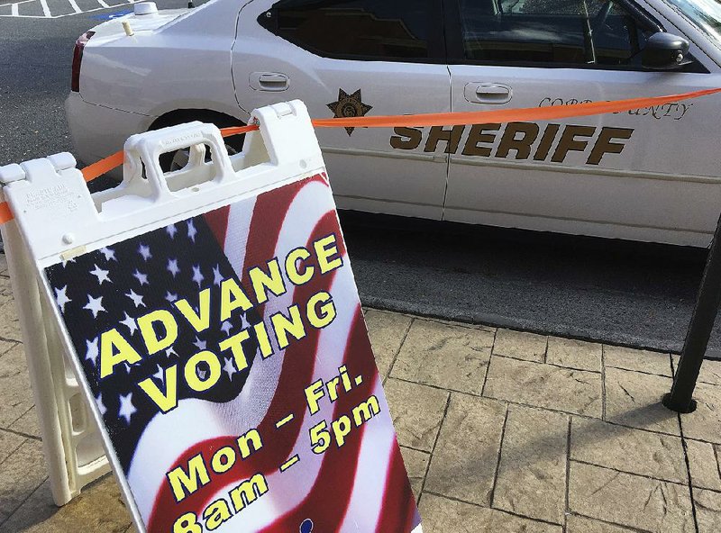 A Cobb County, Ga., sheriff’s deputy keeps watch outside an early-voting site Monday in Marietta.