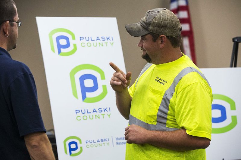 Wildon Haile (right), superintendent of a shop that will produce new signs for Pulaski County, speaks with computer coordinator Chad Truby, who designed a new county smartphone app, during a ceremony Tuesday at the Pulaski County Administration Building in Little Rock. 