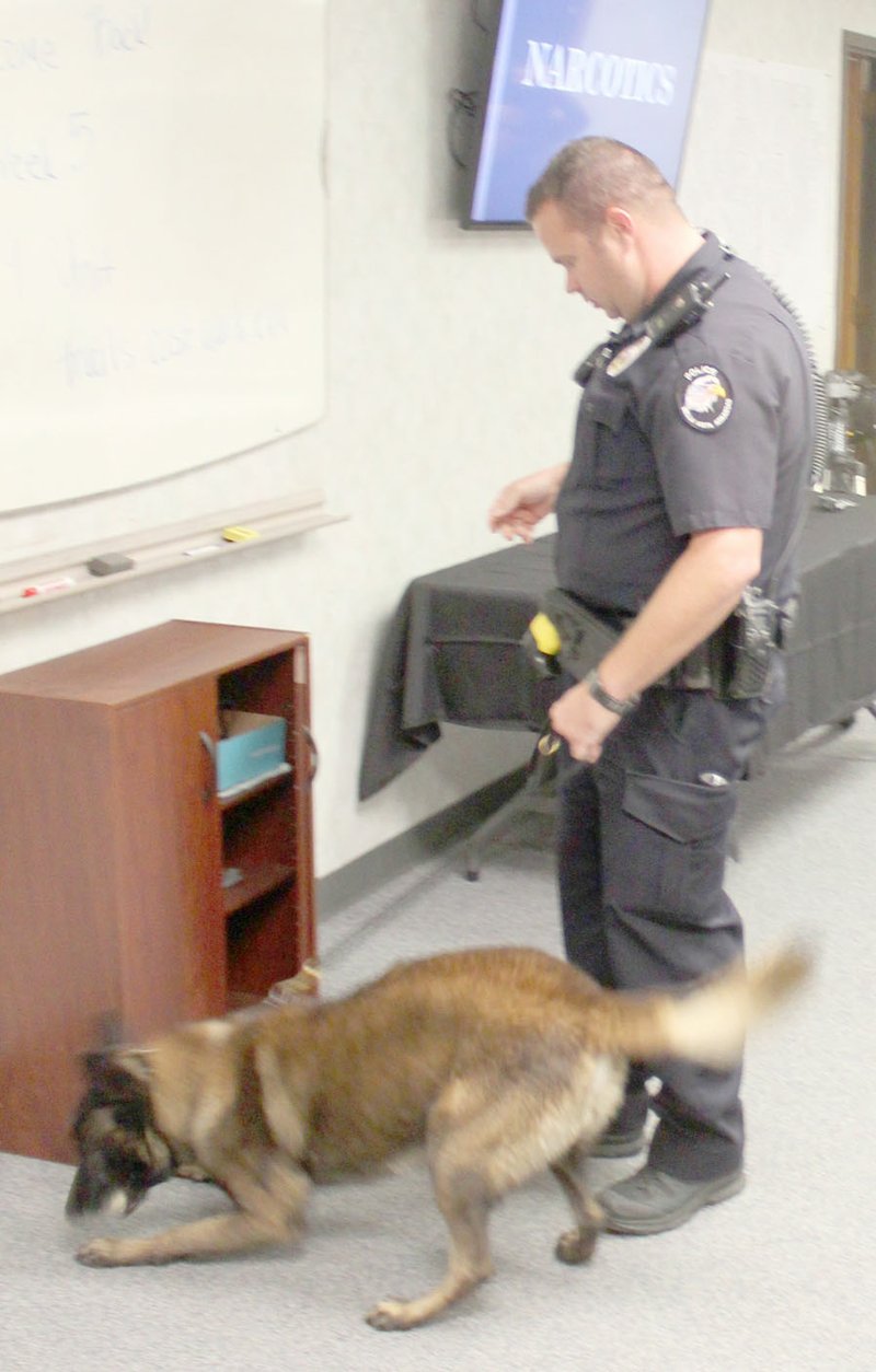 Keith Bryant/The Weekly Vista The Bella Vista Police Department&#8217;s K9, Camo, left, is rewarded with a tennis ball after finding a small stash of marijuana that his handler, corporal J.D. Jordan, had hidden in a small cabinet to demonstrate the dog&#8217;s drug-sniffing ability during the citizen police academy&#8217;s K9 and narcotics session.