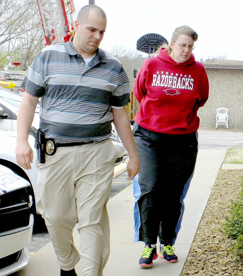 File photo/NWA Democrat-Gazette Cathy Lynn Torres, 43, is brought into the Bella Vista Police Department by Sgt. Clayton Roberts in March 2015. She was arrested on warrants charging her with capital murder, rape and battery in the first degree in the death of her 6-year-old son.