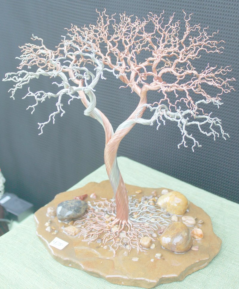 Keith Bryant/The Weekly Vista Ed Bratton, a Rogers resident, had several of his wire trees for sale at the Bella Vista Arts and Crafts Festival. The aluminum, copper and brass wires are wound together by hand, he said, and then sealed with an epoxy glaze to prevent tarnishing and hold them to the base, which is often a local stone.