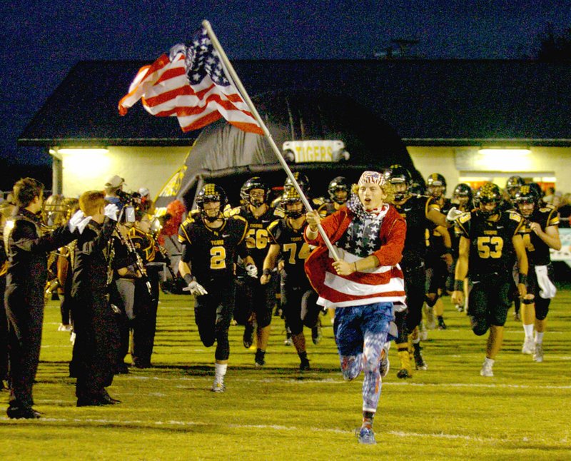 MARK HUMPHREY ENTERPRISE-LEADER &#8220;Oh, say does that star spangled banner yet wave.&#8221; Prairie Grove senior Taylor Moore leads the Tiger football team out of tunnel and through a spirit line out onto the field. The Tigers knocked off previously unbeaten Pea Ridge, 42-21, Friday.