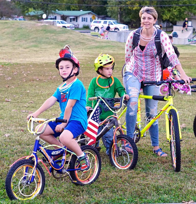 Photo by Randy Moll Piper and Gus Franzen wait with their mother, Amber, for the start of the Glow Ride held in Gentry on Saturday night. The ride started in the park and followed a designated route through the north side of the city and then returned down Main Street to the park.