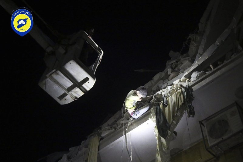 In this photo released early Monday, Oct. 17, 2016 and provided by the Syrian Civil Defense group known as the White Helmets, rescue workers try to remove a boy stuck in the debris of a building in the neighborhood of Qaterji in rebel-held east Aleppo following an airstrike in Aleppo, Syria. 