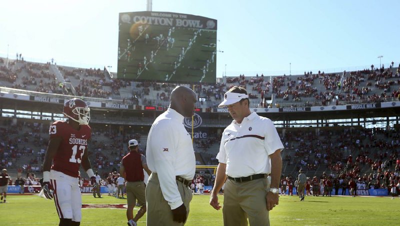 Oklahoma Coach Bob Stoops (right) and Texas Coach Charlie Strong talk on the field before their game Oct. 8. The Big 12 has decided against expansion and intends to stay at 10 schools, but the league is thinking about splitting its members into divisions.