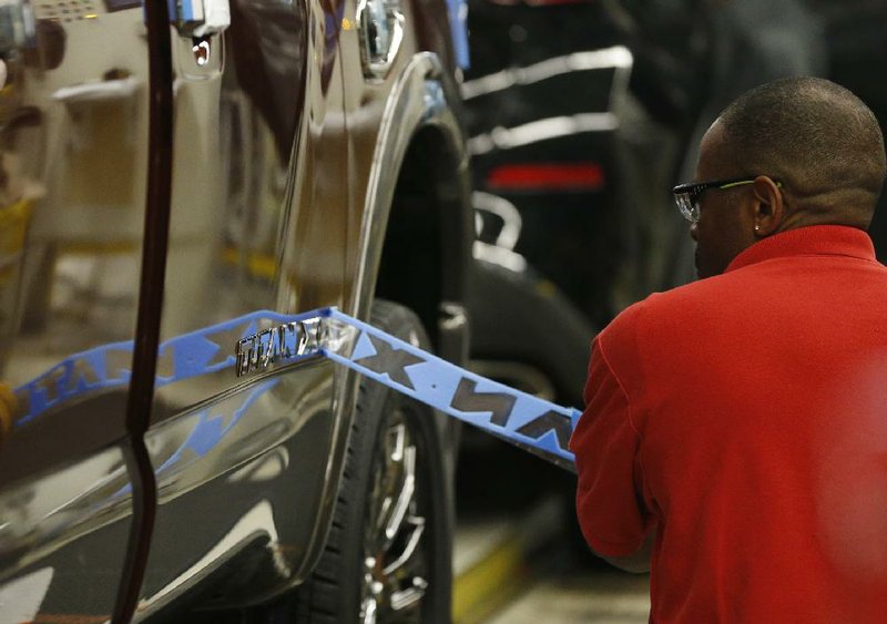 An assembly line worker applies a logo stencil to the side of a Titan pickup at the Nissan Canton Vehicle Assembly Plant in Canton, Miss., in April. A Federal Reserve report released Wednesday showed mixed results for auto sales in the central bank’s regions. 