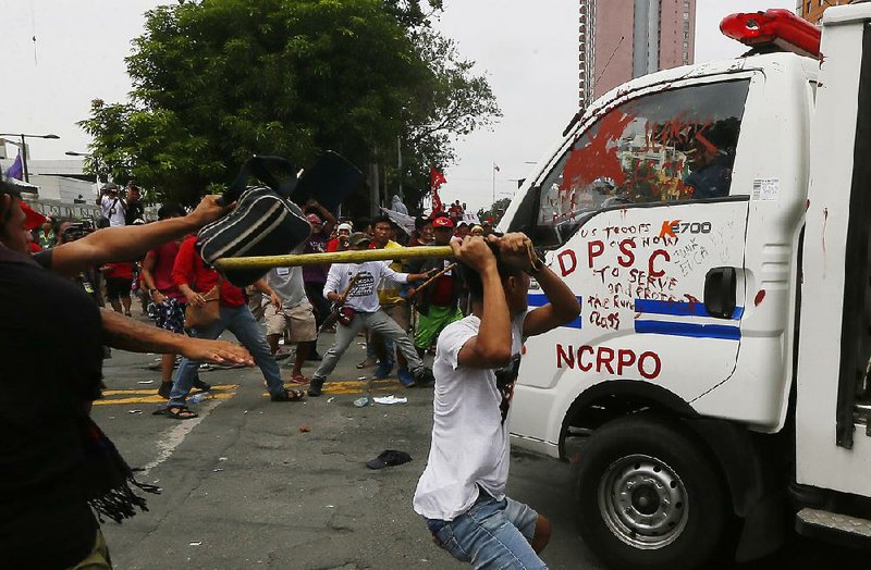 Philippine protesters attack a police van Wednesday after it rammed into demonstrators outside the U.S. Embassy in Manila. The driver said he was trying to escape the crowd.