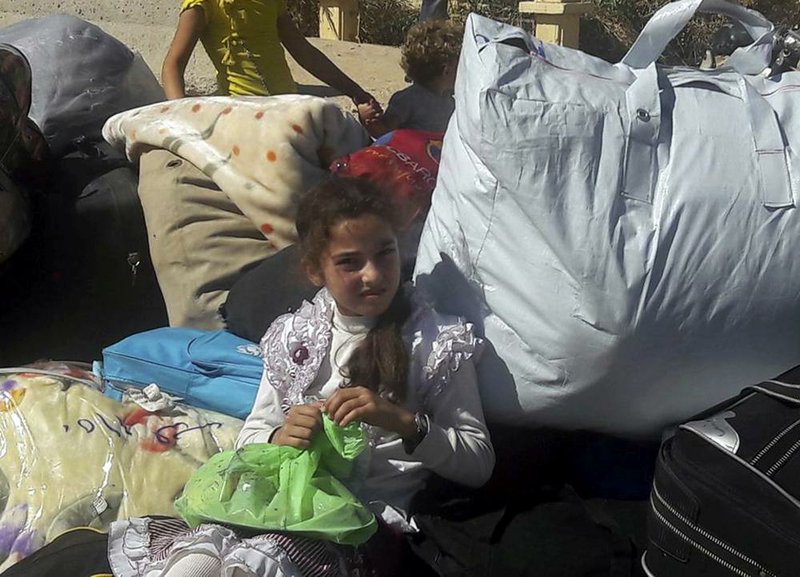 A Syrian girl sits on her belongings Wednesday as she waits to leave the besieged Damascus suburb of Moadamiyeh.