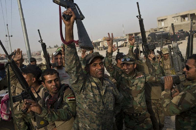 Iraqi soldiers raise their weapons in celebration Wednesday on the outskirts of Qayyarah, Iraq. 