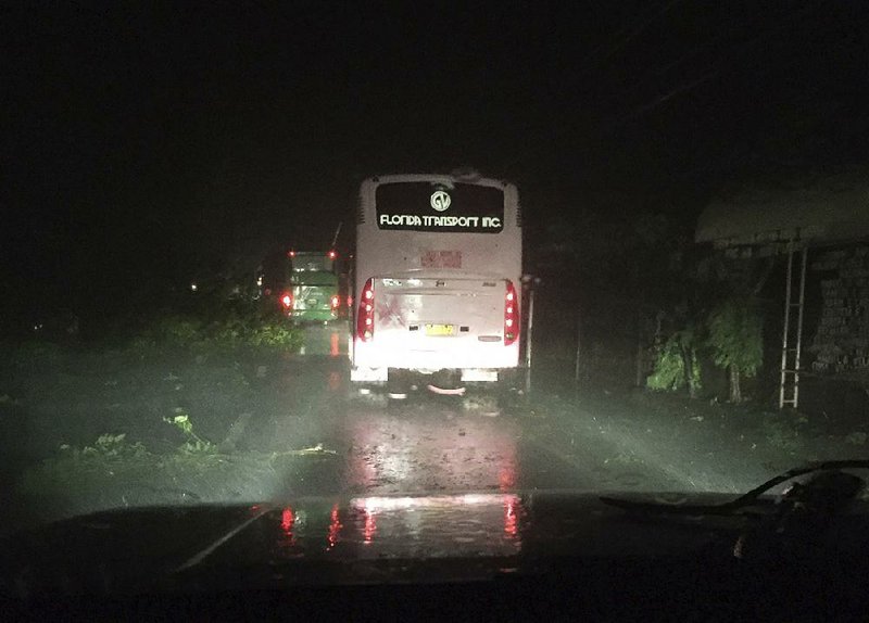 Passenger buses in Narvacan, Philippines, travel this morning around trees toppled by Typhoon Haima. 