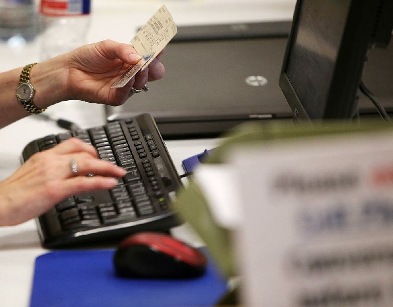 Kim Buckley, the Madison County, Tenn., elections administrator, checks a voter’s ID on Wednesday in Jackson on the first day of early voting in Tennessee.