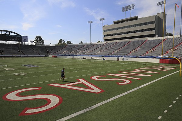 A runner does laps around the field Wednesday afternoon at war Memorial Stadium in Little Rock. Gov. Asa Hutchinson is proposing cutting state general funding almost in half for War Memorial Stadium operations in the fiscal year starting July 1, 2018.