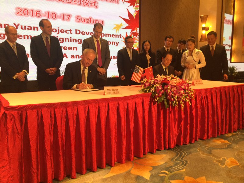 Governor Asa Hutchinson signs a memorandum of understanding with Chinese officials from the Suzhou Tianyuan Garments Company.