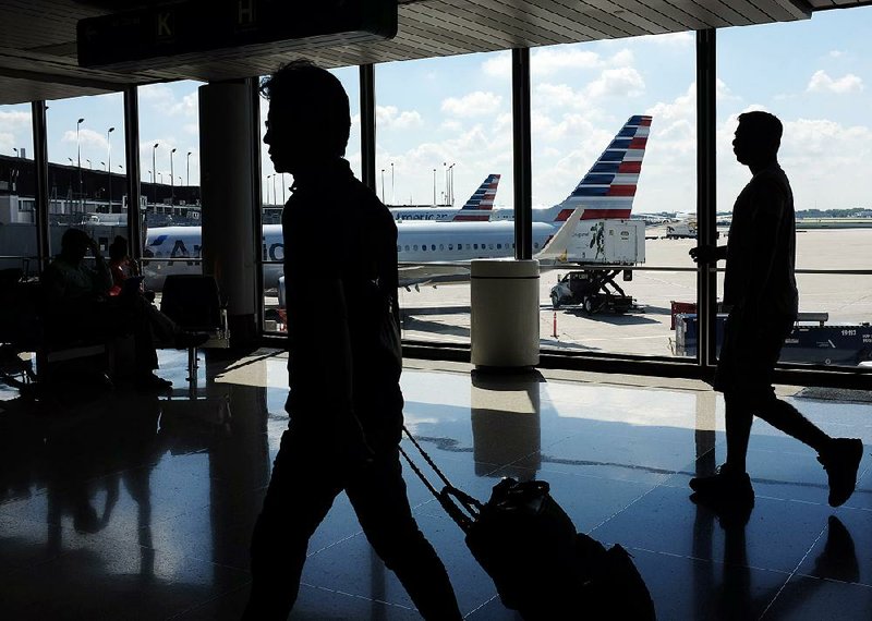 Passengers walk to their gates as American Airlines planes wait to depart at O’Hare International Airport in Chicago during the summer.
