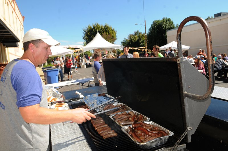 Russell Ellis grills bratwursts during last year’s Rogers Octoberfest — now OktoBeerFest, with even more activities for families.