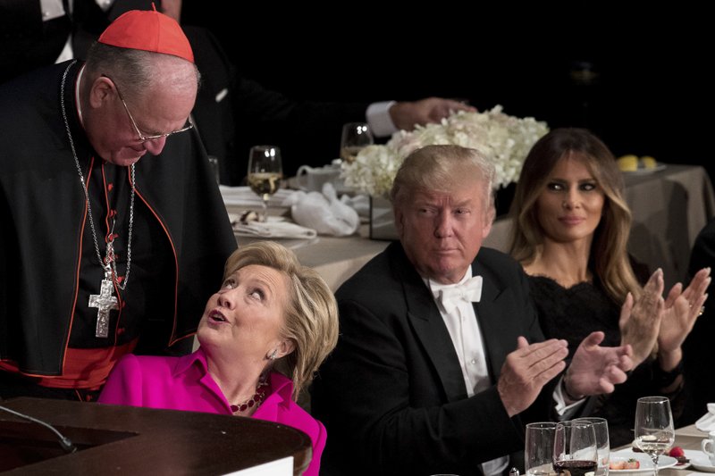 Republican presidential candidate Donald Trump, second from right, and his wife Melania Trump, right, watch as Democratic presidential candidate Hillary Clinton, second from left, is helped into her chair by Cardinal Timothy Dolan, Archbishop of New York, left, after speaking at the 71st annual Alfred E. Smith Memorial Foundation Dinner, a charity gala organized by the Archdiocese of New York, Thursday, Oct. 20, 2016, at the Waldorf Astoria hotel in New York. (AP Photo/Andrew Harnik)
