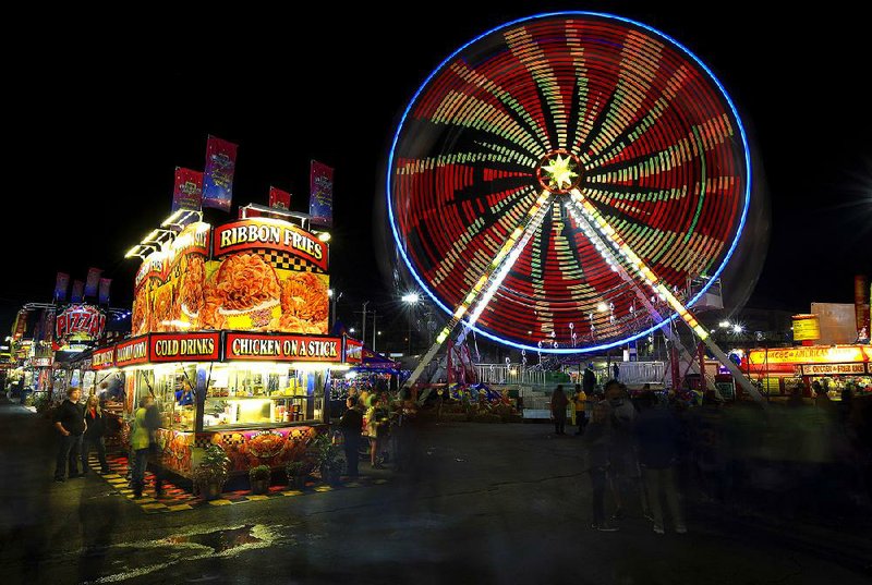 Arkansas Democrat-Gazette/STATON BREIDENTHAL --10/20/16-- Visitors to the Arkansas State Fair walk the midway Thursday night as rides and food booths light up the night sky. 