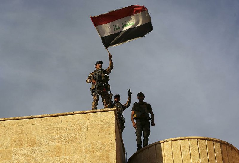 Iraq’s elite counterterrorism forces raise an Iraqi flag Friday after retaking Bartella, a city less than 10 miles from Mosul, from Islamic State forces.