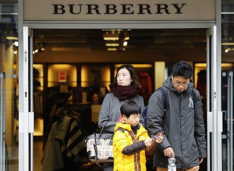 Shoppers exit a Burberry store in London on Friday. Lower prices for jewelry and handbags are drawing tourists to England, where a drop in the value of the pound has made luxury items more affordable for foreigners. 