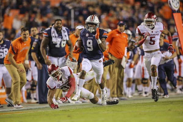 Arkansas' Dwayne Eugene, bottom left, falls to the ground as Auburn's Kam Martin, center, outruns him and Arkansas' Henre' Toliver , right, as Martin run in his team's 8th touchdown during the fourth quarter of their game Saturday at Jordan-Hare Stadium in Auburn, Ala.