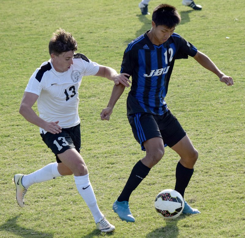 Photo courtesy of JBU Sports Information John Brown University junior forward Steve Teshima tries to keep the ball away from a Southwestern Christian (Okla.) defender during Tuesday&#8217;s game. The teams played to a 1-1 draw in double overtime.