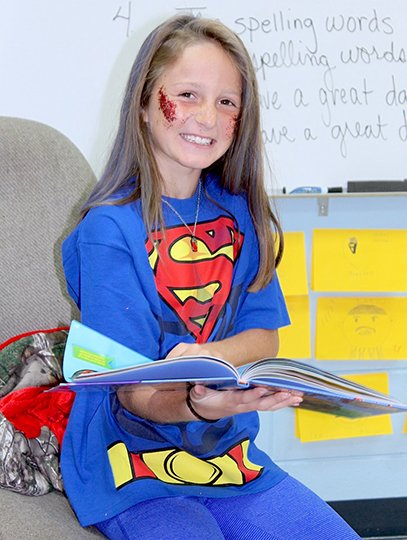 Submitted photo Magnet Cove Elementary School third-grader Karstyn Scrivner builds her vocabulary power during reading time on Super Hero Day of Magnet Cove Spirit Week.