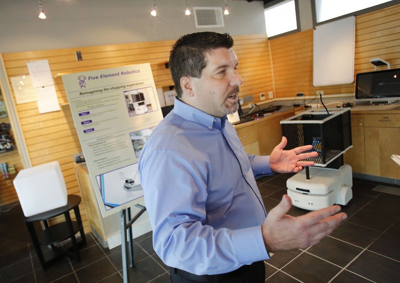 Clint Johnson, interim director of the McMillon Family Retail Innovation and Technology Lab, describes a robotic shopping cart, shown to the right of him.