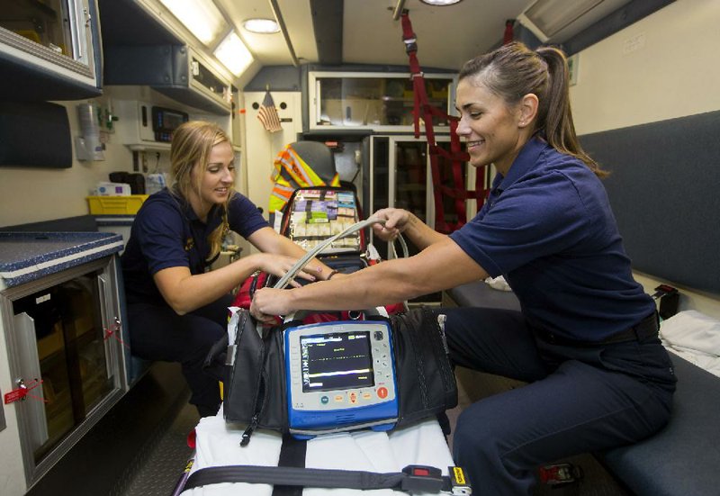 Rogers Fire Department firefighter/emergency medical techs Kari Crump (left) and Lacie Hewlett check equipment Oct. 14 at Rogers Fire Department Station 1 in downtown Rogers.