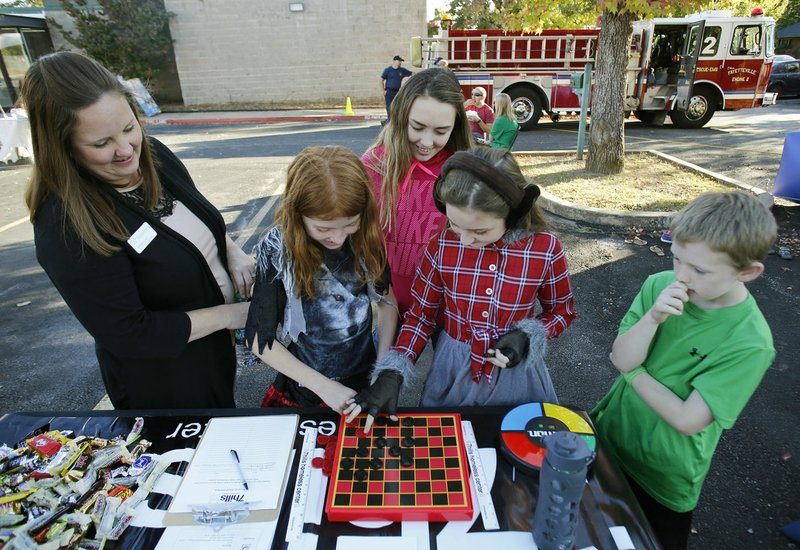 Brittney Gulley (from left), director of development at WelcomeHealth, watches Courtney Niesiur, 9, Macey Jones, 15, Bree Ray, 9, and Jesse Ray, 8, play a game of checkers Friday, October 21, 2016, during a 30th year celebration at the clinic in Fayetteville. The clinic was formerly known as the Northwest Arkansas Free Health Clinic.