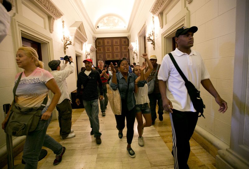 Pro-government supporters force their way into the National Assembly in Caracas, Venezuela, Sunday, Oct. 23, 2016. The government supporters interrupted a special congressional session where lawmakers were discussing bringing legal charges against President Nicolas Maduro. 