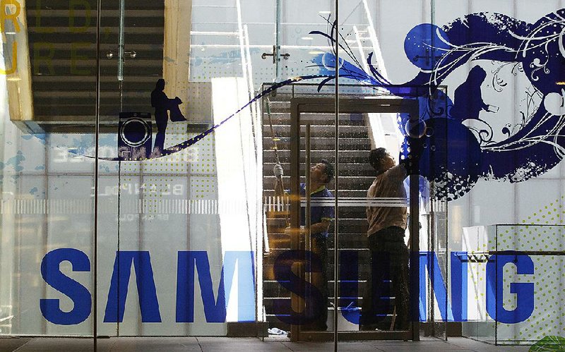 Workers clean a window at a Samsung Electronics shop in Seoul, South Korea, earlier this month. The company this month stopped sales of its Galaxy Note 7, the fi re-prone smartphone at the center of a lawsuit filed Monday by South Korean consumers.