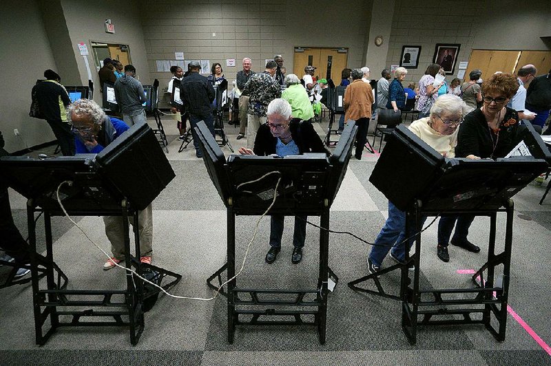 Voters make their choices Monday during the start of early voting at the Laman Library in North Little Rock. Some counties reported that the number of voters Monday exceeded the number who cast ballots on the fi rst day of early voting in 2012, the previous presidential election.