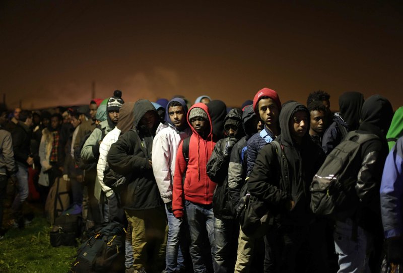 Migrants line-up to register at a processing centre in the makeshift migrant camp known as "the jungle" near Calais, northern France, Monday Oct. 24, 2016. 