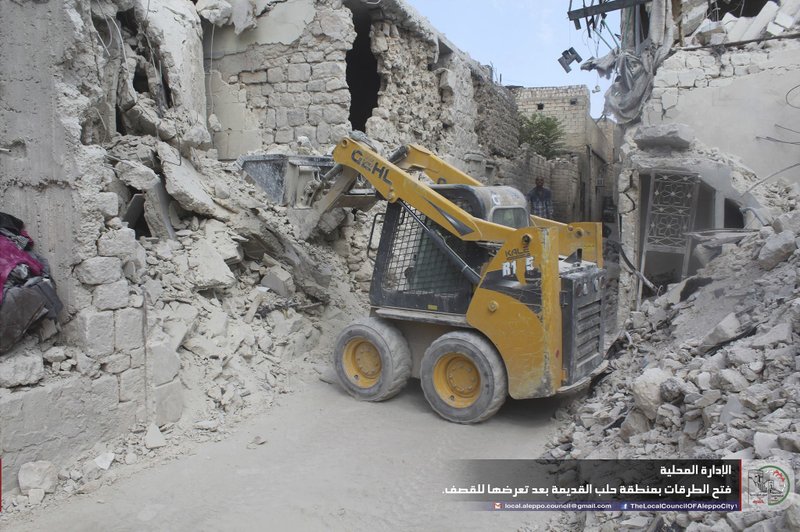 In this photo taken Sept. 26, 2016 and provided by the local council of Aleppo city, Syrians workers clean damaged after airstrikes, in Aleppo, Syria. 
