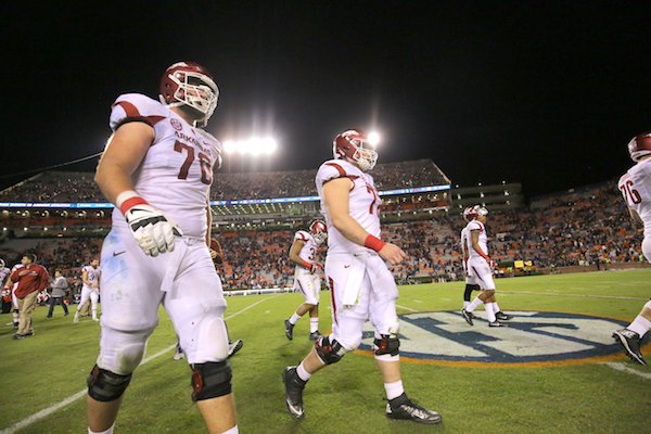 Arkansas' Dan Skipper, left, and other player walks off the field after their loss Saturday at Jordan-Hare Stadium in Auburn, Ala.