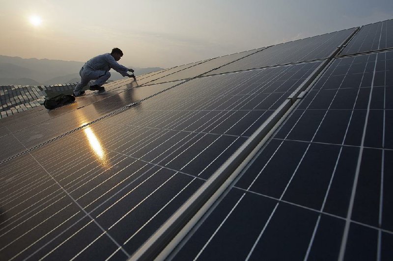 A worker repairs solar panels at a power station in Songxi county in China’s Fujian province in August. A global glut in solar panels is being blamed by some on Chinese manufacturers that are subsidized by the government. 