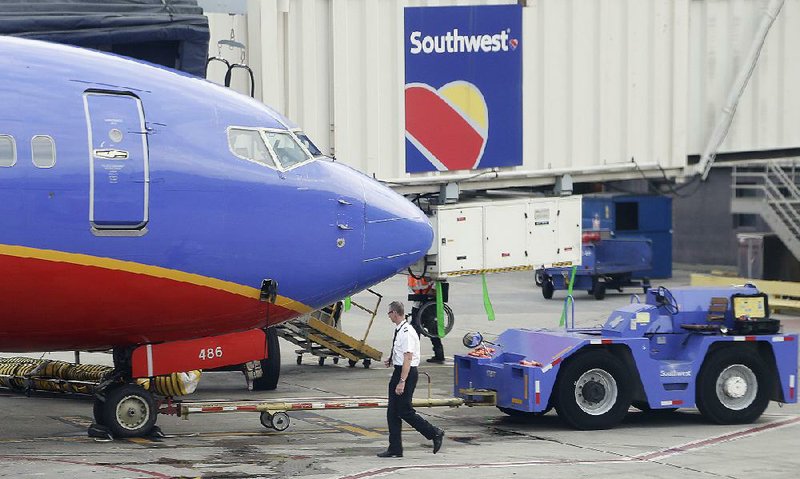 A Southwest Airlines pilot performs a preflight check at the airport in Atlanta. Southwest says it carried more passengers in its third quarter but airfares were lower. 