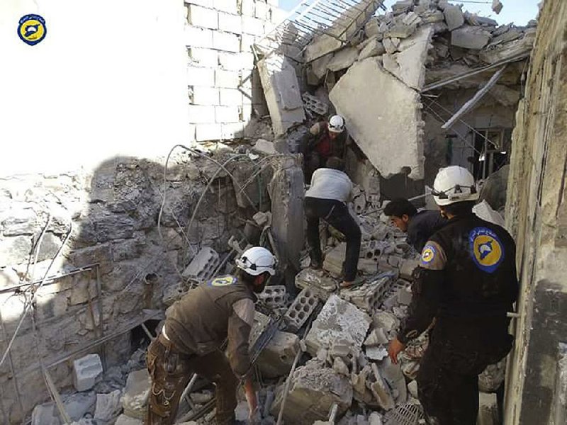 Syrian rescuers search the rubble Wednesday in the village of Hass after airstrikes that first responders said killed more than a dozen people, most of them children