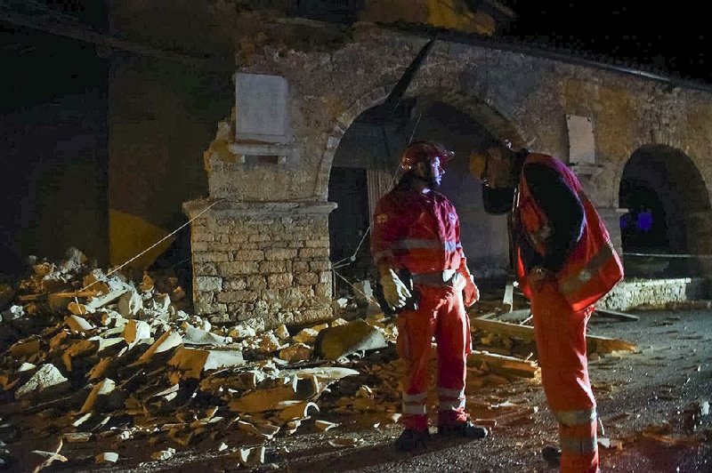 Rescuers stand in earthquake rubble Wednesday in the village of Visso in central Italy.