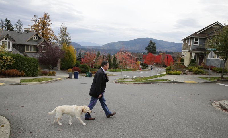 In this photo taken Oct. 24, 2016, Sen. Mark Mullet, D-Issaquah, walks with his dog Arthur as he rings doorbells of registered voters in Issaquah, Wash.