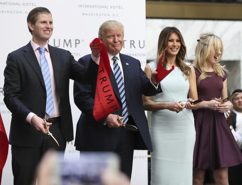 Republican presidential candidate Donald Trump, together with his family, from left, Eric Trump, Melania Trump and Tiffany Trump, waves part of a ribbon after cutting the ribbon during the grand opening of Trump International Hotel in Washington, Wednesday, Oct. 26, 2016. Donald Trump and his children hosted an official ribbon cutting ceremony and press conference to celebrate the grand opening of his new hotel. (AP Photo/Manuel Balce Ceneta)