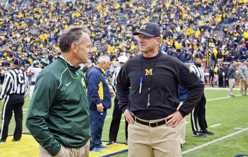 Michigan State head coach Mark Dantonio, left, chats with Michigan counterpart Jim Harbaugh in this file photo. Rising to No. 2 nationally with Ohio State's loss to Penn State, Michigan goes on the road against Michigan State this week.
