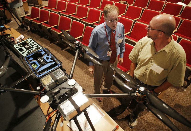 Jim Robbins (left) and Larry Purcell, both with the University of Arkansas Division of Agriculture, discuss Thursday the variety of unmanned aircraft on display at the UAS Summit at the University of Arkansas Global Campus in Fayetteville.