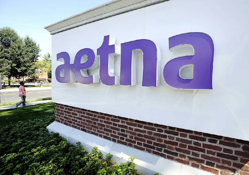 A pedestrian passes a sign for Aetna Inc. outside the insurance company’s Hartford, Conn., headquarters in this file photo. Aetna on Thursday reported a quarterly profi t of $603.9 million.